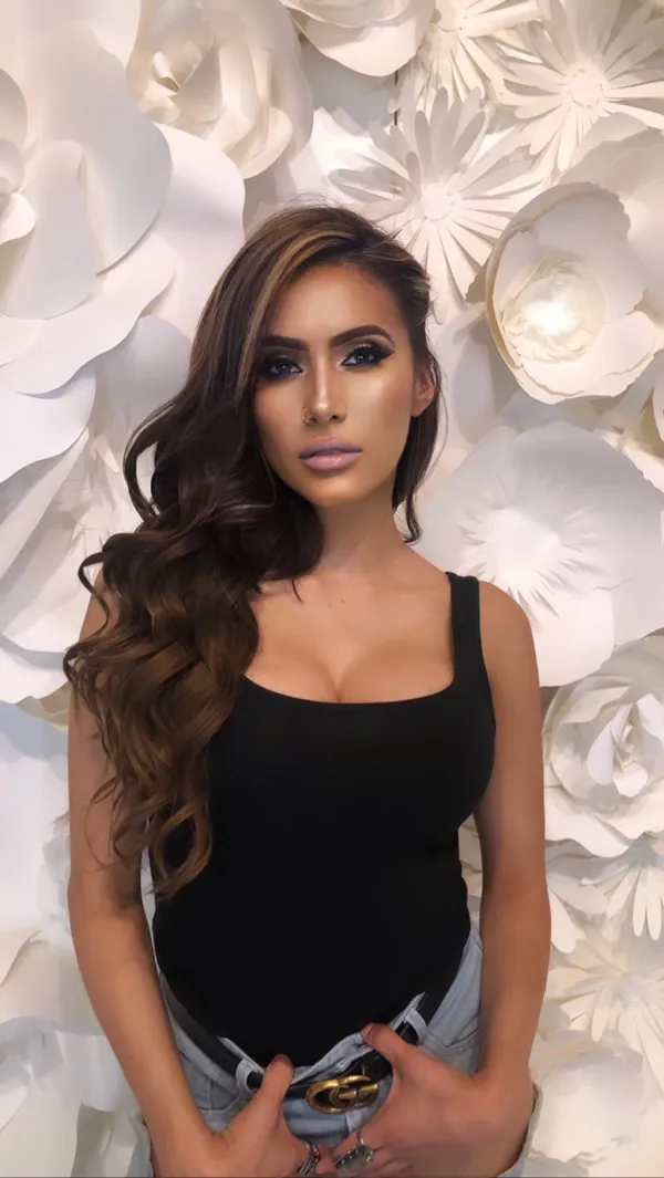 Portrait of Cristina Vee in a black tank top in front of large white paper flowers.