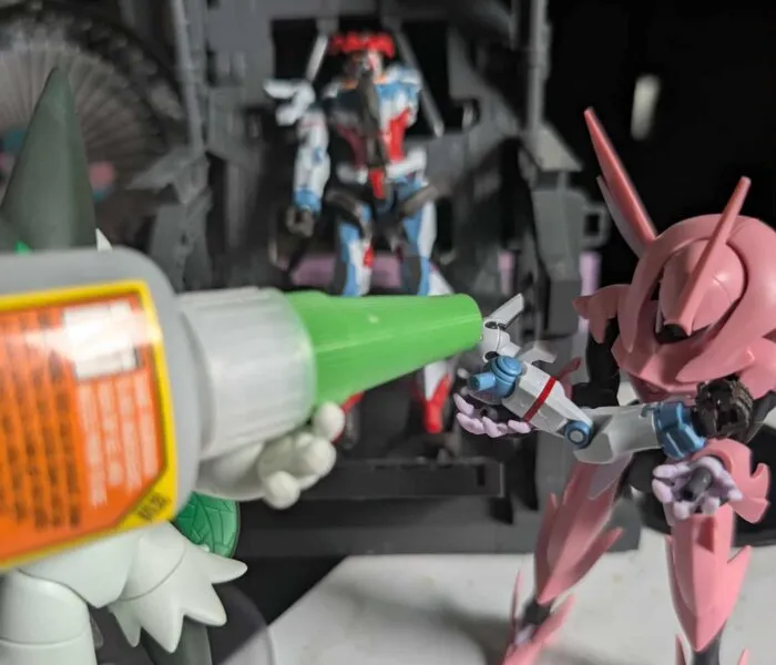 A close-up of a green-tipped applicator applying glue to a small Gunpla part.