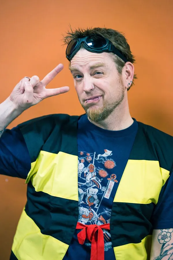 Portrait of Zack Davisson, wearing goggles and making a peace sign.