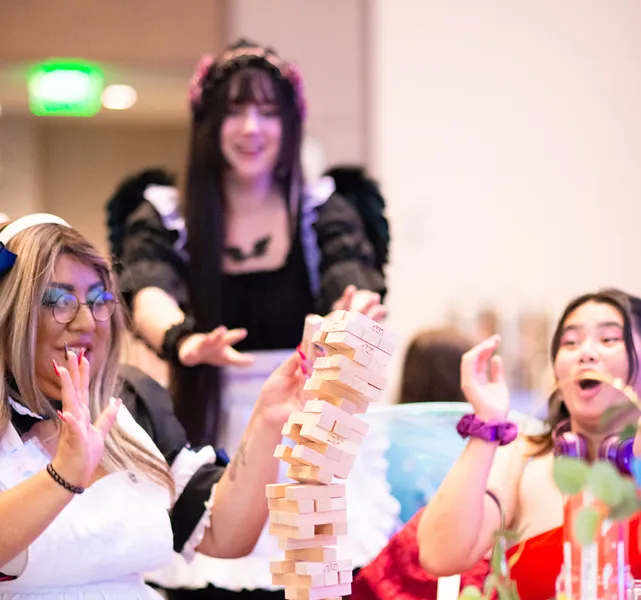 Maid cafe staff and guests laughing while playing a game of Jenga.