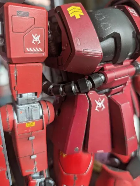 Close-up of a red Gunpla model showing intricate mechanical details and small decals.