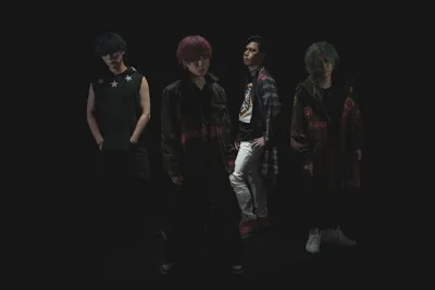 Portrait of the four members of the band ACME in dark clothing against a black background.