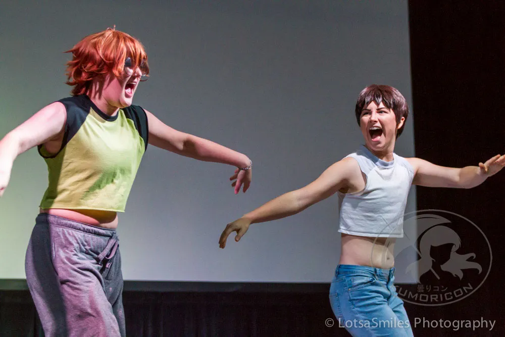 Two performers in casual cosplay shouting and gesturing energetically on stage during the 2017 Lip Sync Showdown.