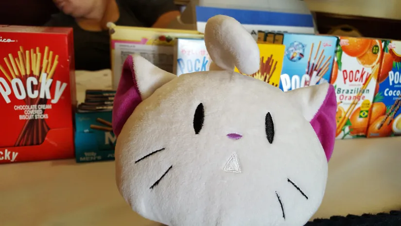 Close-up of a white plush cat head with pink ears and small black eyes.