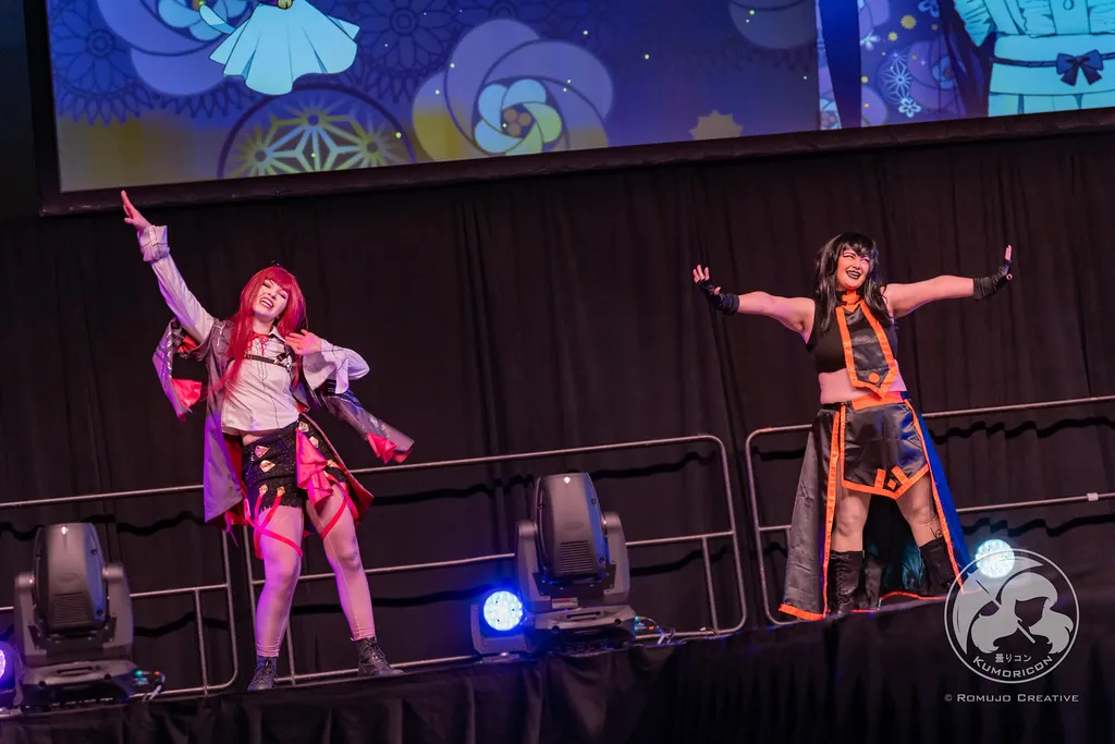 Two performers in high-energy poses on stage during their lip sync performance.