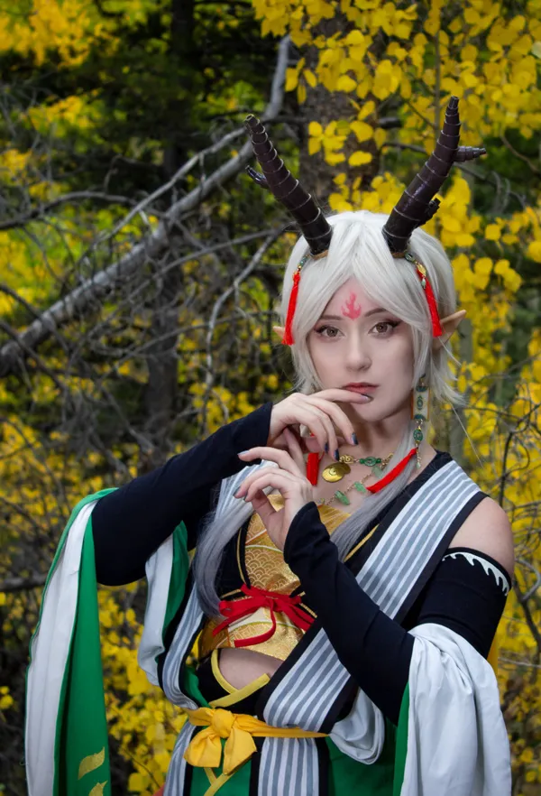 Portrait of December Wynn in a detailed cosplay with horns and white hair against a forest background.