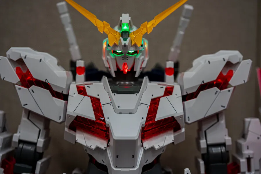 Close-up of a built Unicorn Gundam model kit with glowing red and green LED lights.