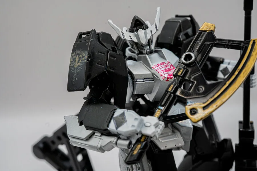 Close-up of a white and black Gunpla model kit holding a large golden axe.