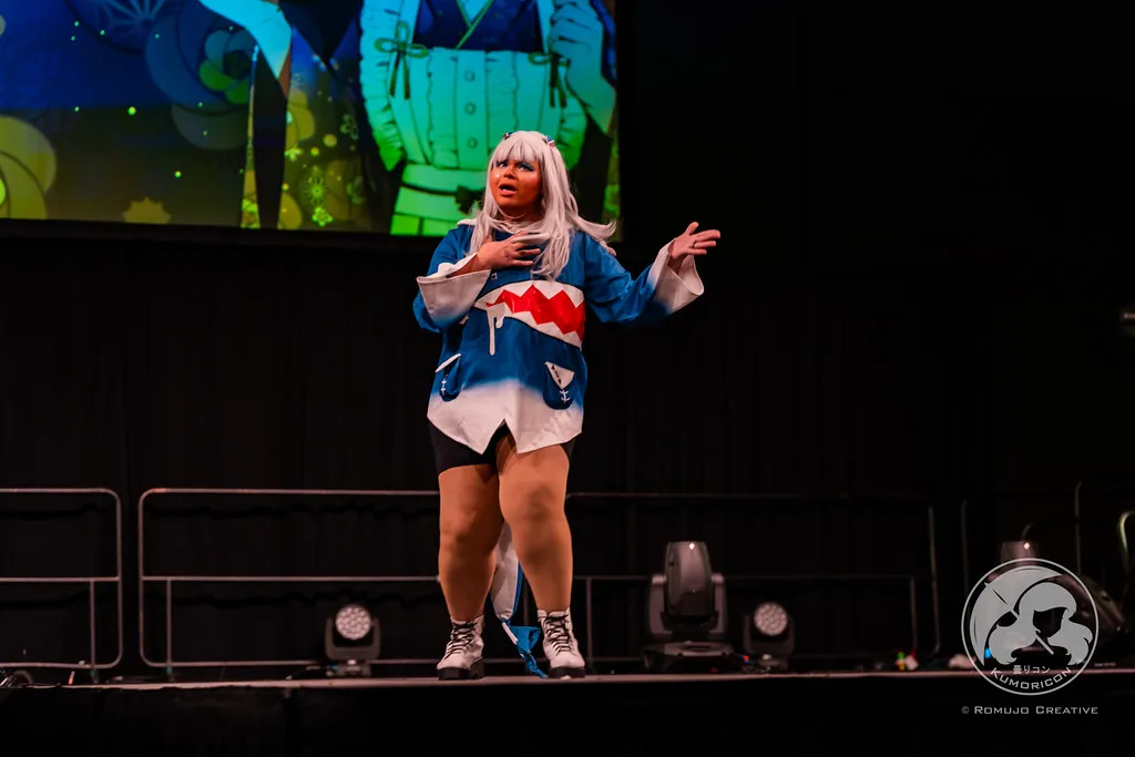 A performer in a Gawr Gura cosplay singing on stage during the 2023 Lip Sync Showdown.