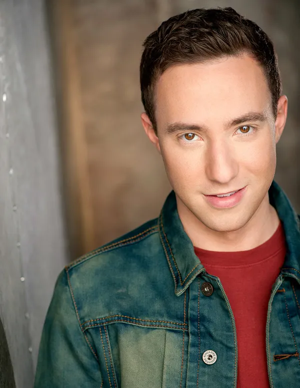 Portrait of Max Mittelman smiling, wearing a denim jacket over a red shirt.